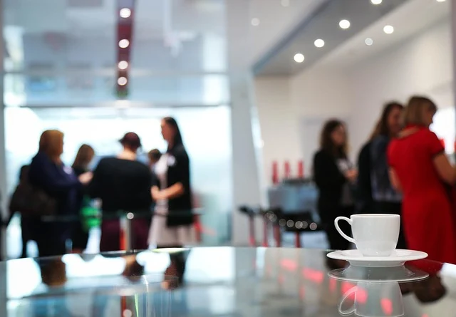 A blurred image of people networking at an event with a coffee cup.