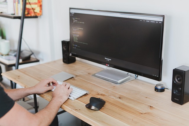 A person typing on a keyboard in front of a monitor