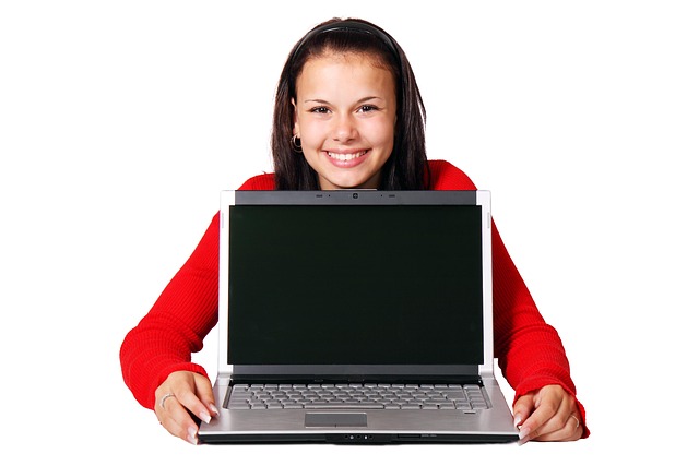 A smiling young woman sitting behind an open laptop
