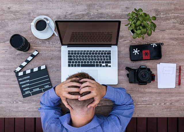 A stressed person holding his head in front of a laptop
