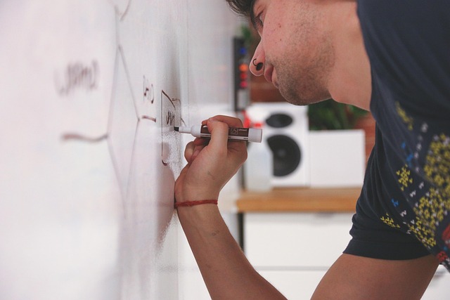 A man drawing a diagram on a whiteboard with a marker