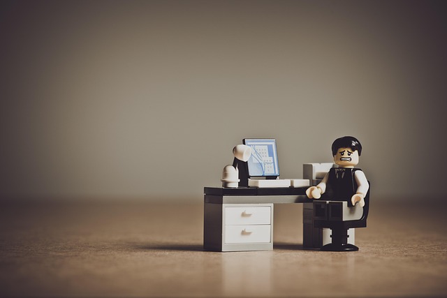 A stressed Lego office worker sitting at a desk with a computer
