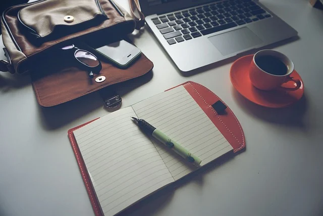 Laptop, notebook, coffee, and bag on a desk