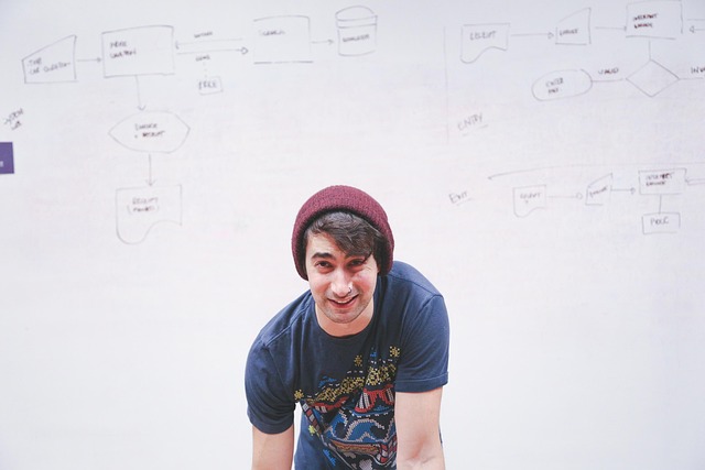 A man standing in front of architectural flowcharts on a whiteboard