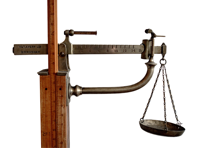 A vintage mechanical balance scale with a hanging pan
