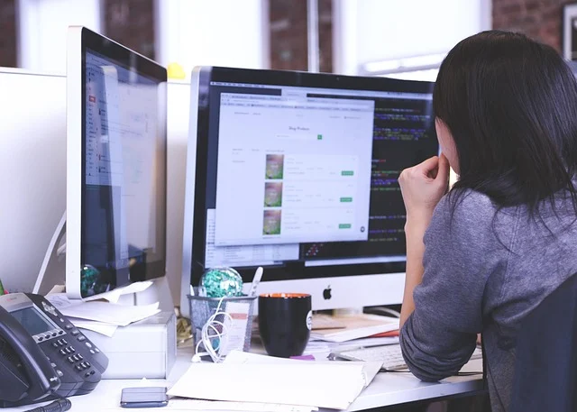 A person working on a computer with code and a website visible.