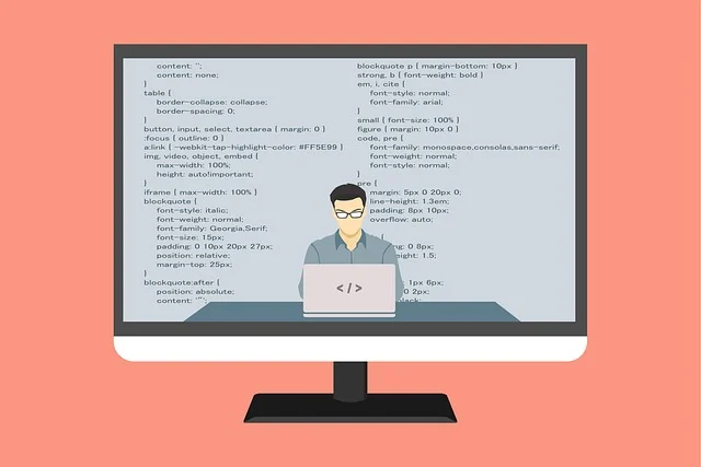 A person coding on a laptop, with code displayed on a large monitor.