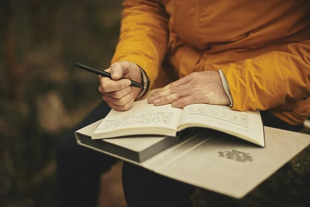 A person writing in a notebook, suggesting study or careful work.