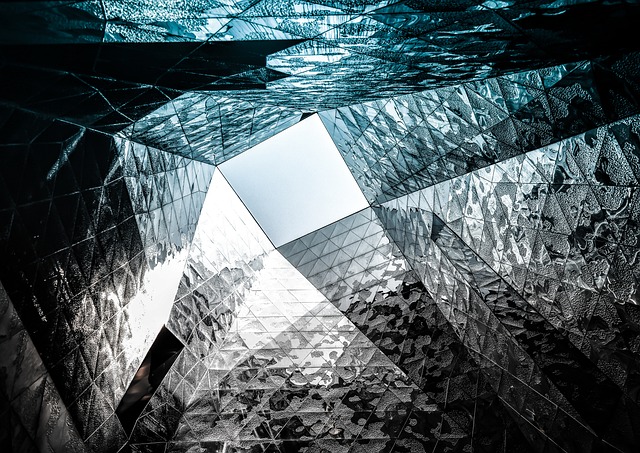 Geometric glass architectural structure looking up toward the sky