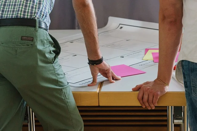 People looking at documents on a table, possibly discussing design or budget.