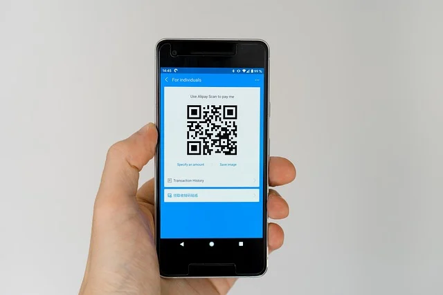 React Native App Development: A hand holding a smartphone displaying a QR code for payment.