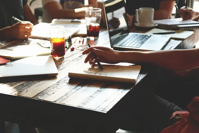 People working together at a table with laptops and notebooks.