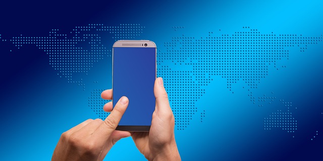Hands holding a smartphone against a digital world map background
