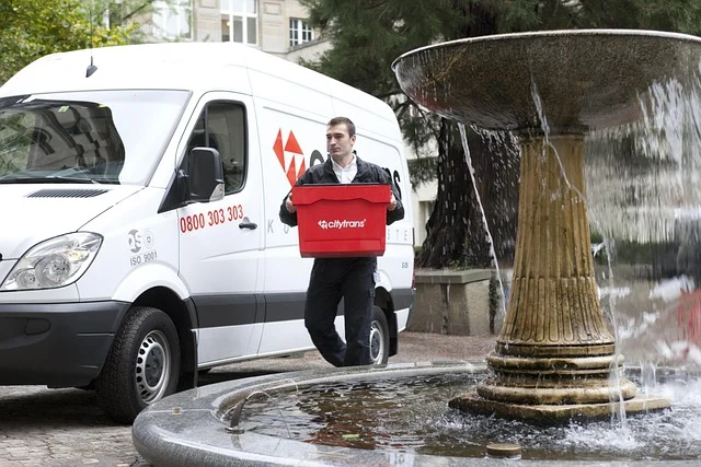 A courier carrying a crate in front of a delivery van