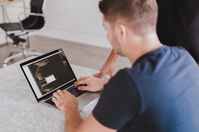 A man coding on a laptop in an office setting