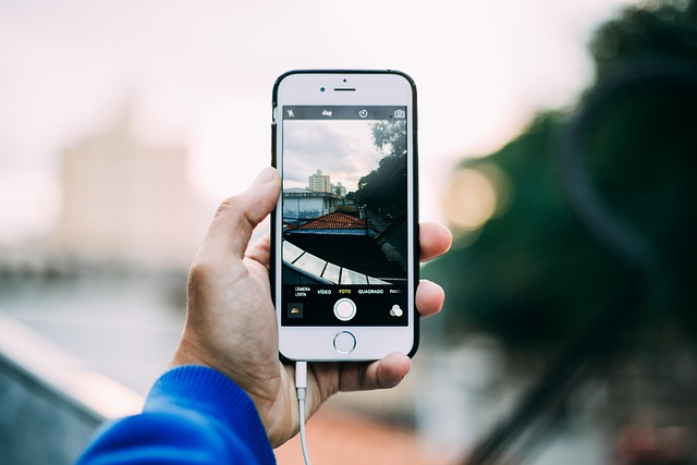 A hand holding a smartphone showing the camera app