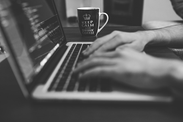 A person typing on a laptop with a coffee mug nearby