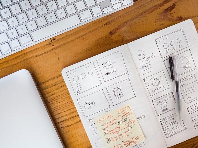 App UI wireframe sketches in a notebook next to a keyboard