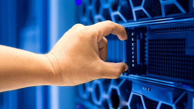 A hand handling a server hard drive in a server rack