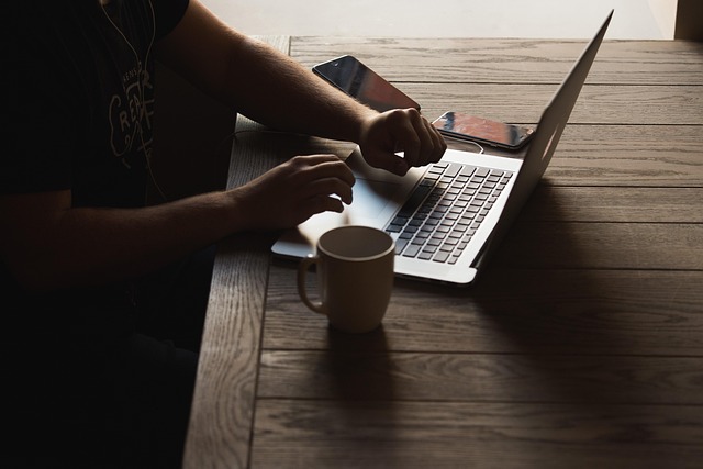 A person working on a laptop at a wooden table