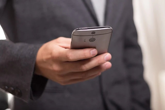 A person in a suit holding a silver smartphone