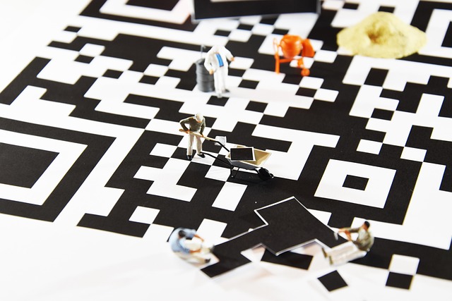 Miniature construction workers building a large black and white QR code