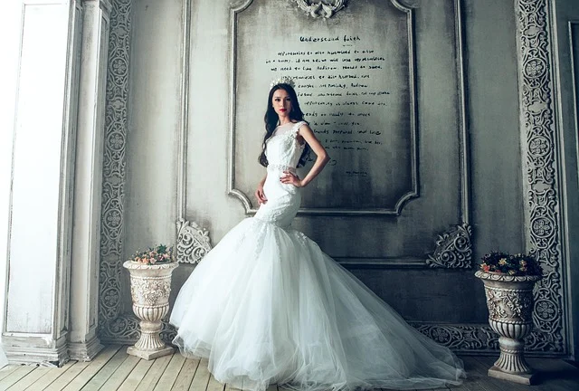 A woman in a white wedding dress posing in a studio.