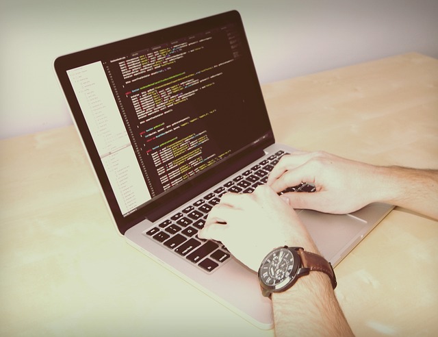 Hands typing code on a laptop computer at a desk