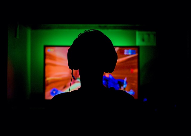 Silhouette of a person wearing headphones playing video games