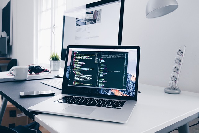 A laptop displaying lines of code on a modern desk setup