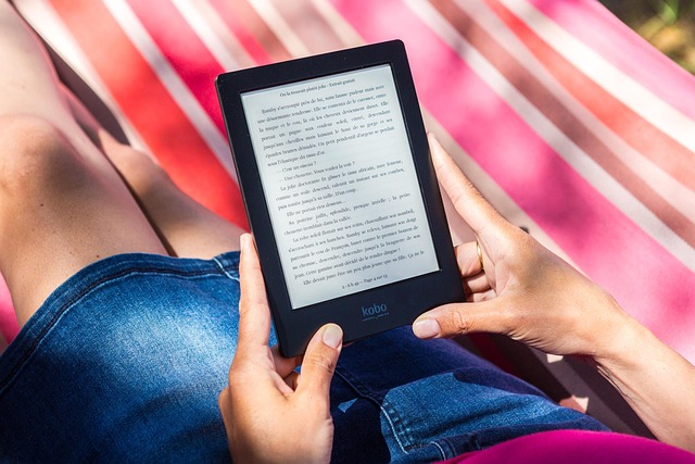A person holding a Kobo E Ink e-reader outdoors