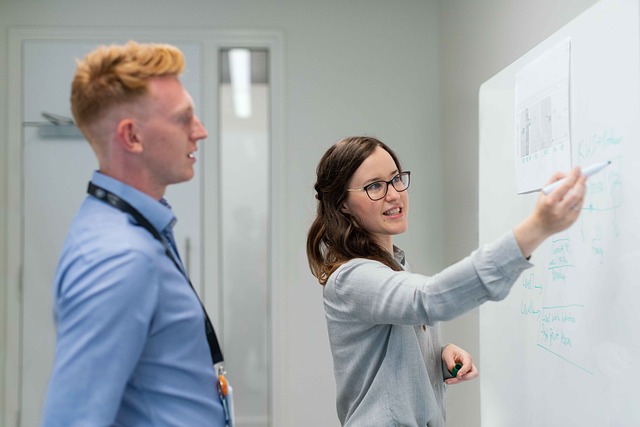 Two colleagues discussing ideas on a whiteboard in an office