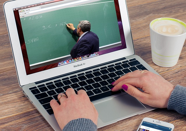 A laptop displaying an online video lecture while a person types