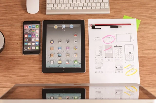 Desk with smartphone, tablet, and mobile app UI wireframe sketches