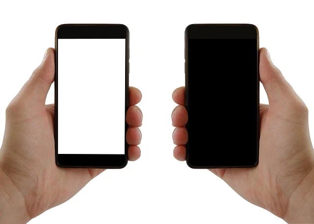 How to find blocked numbers on iphone: Two hands holding smartphones with blank screens