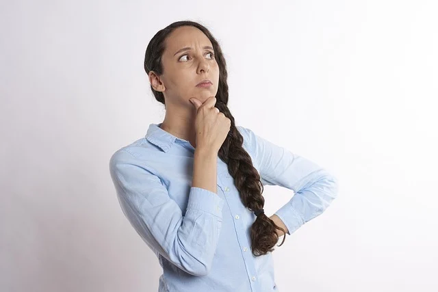 A woman with a thoughtful expression, hand on chin, looking up.