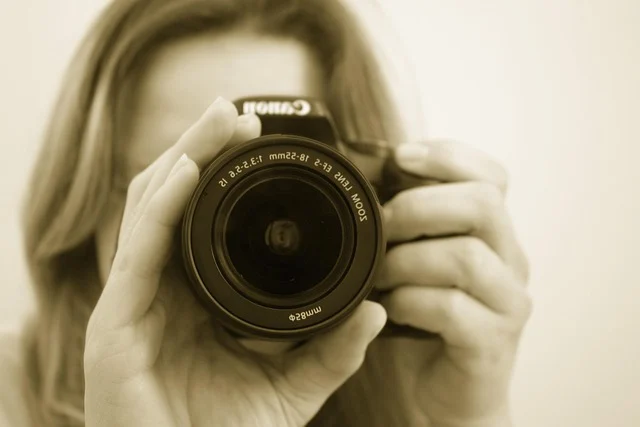 A person holding a Canon DSLR camera taking a picture