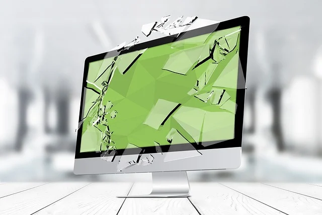 A computer monitor with a shattered screen, showing broken glass pieces.