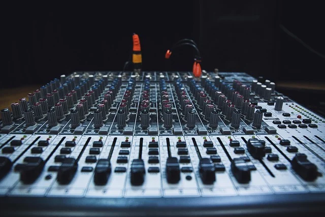 An audio mixer with many knobs and faders.