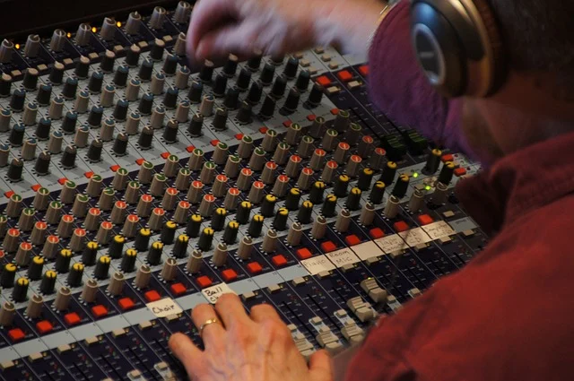 A person adjusting knobs on an audio mixing console.