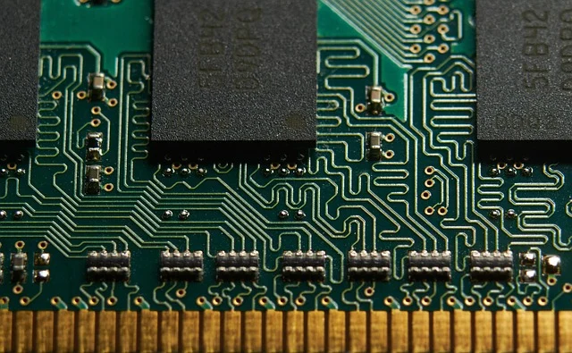 Close-up of a green circuit board with chips and gold contacts