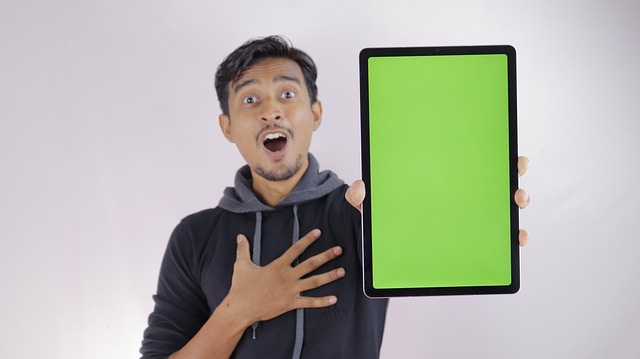 Excited man holding a large tablet with a green screen