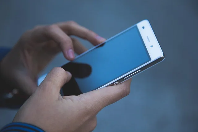 A person's hands holding and interacting with a smartphone.