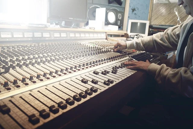 A person's hands adjusting controls on a large audio mixing console.