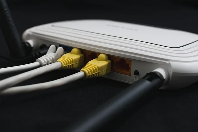 How to change wifi channel: Back of a white Wi-Fi router with cables plugged in.