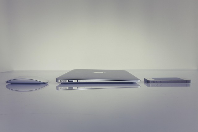 A mouse, a laptop, and a smartphone on a reflective surface