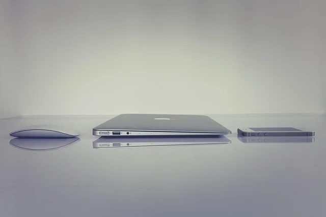 A mouse, a laptop, and a smartphone on a reflective surface