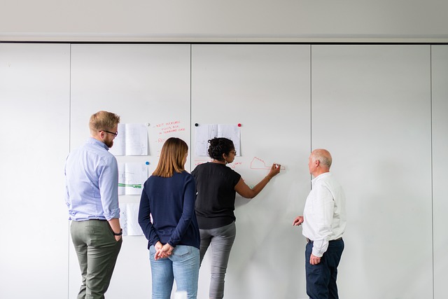A team collaborating and drawing on a whiteboard wall