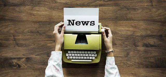 Hands using a typewriter with paper displaying the word News
