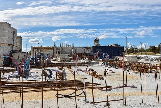 A construction site with rebar, pipes, and concrete blocks under a blue sky.